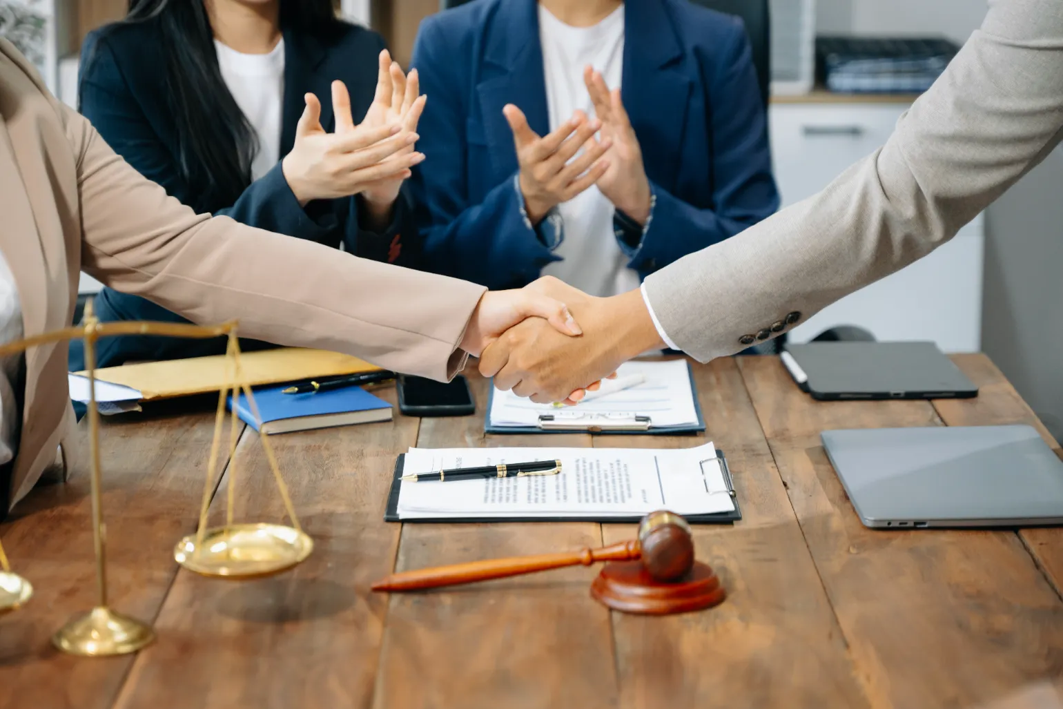 Lawyers on the table handshaking with a scale in the center.