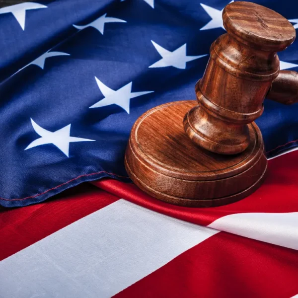 A judge's gavel with an american flag laid on the background.