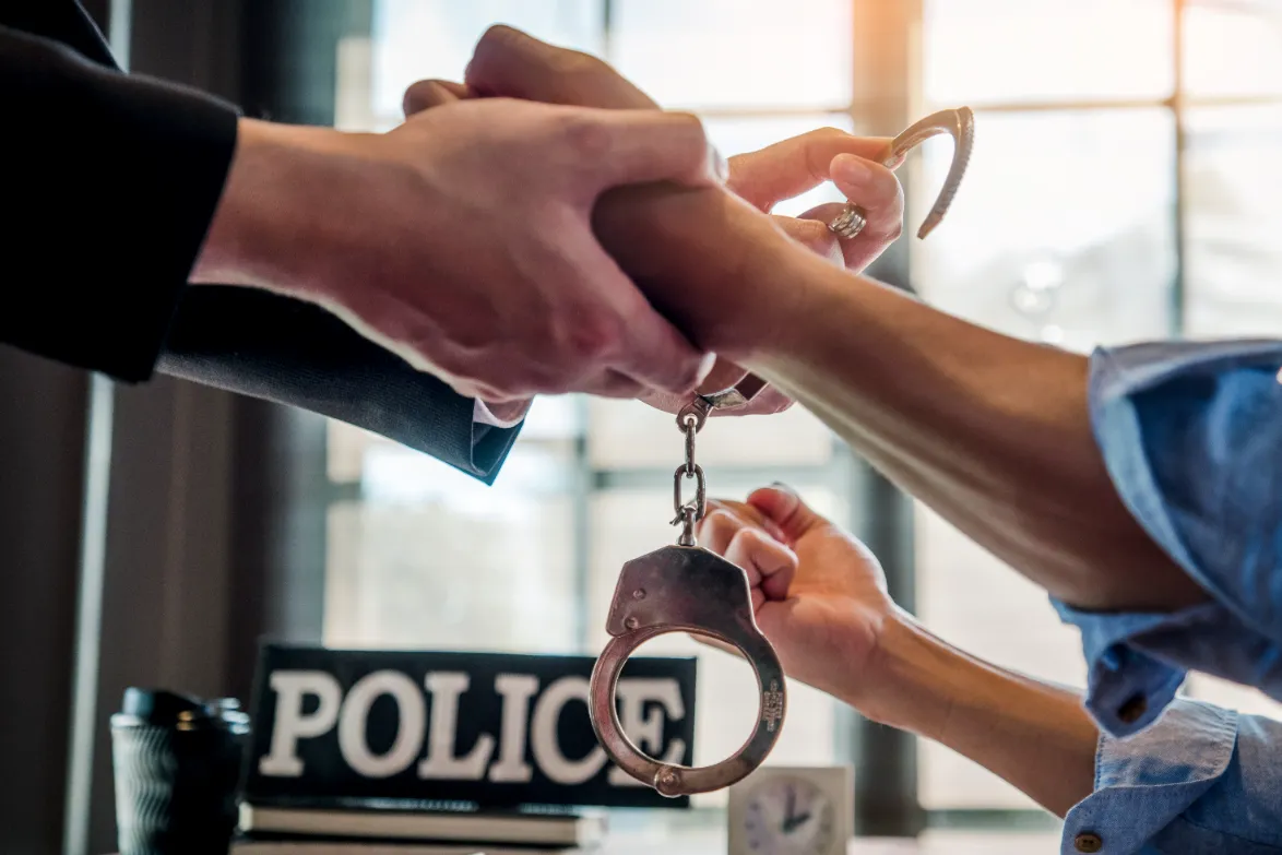 A law enforcement releasing the handcuffs on a suspect.